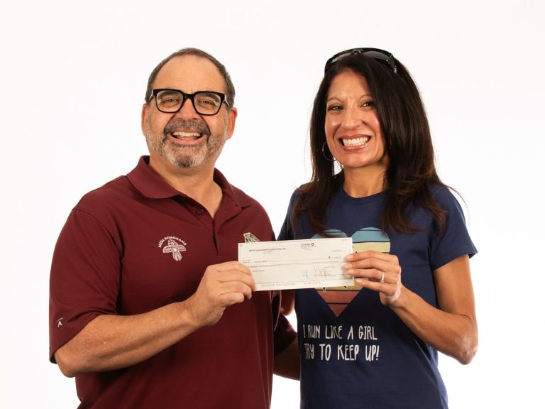 Mesa HoHoKam member, Ivan Martinez presents 50/50 Grant check to We Run Mesa, Nycole Leyba, founder of the group We Run Mesa